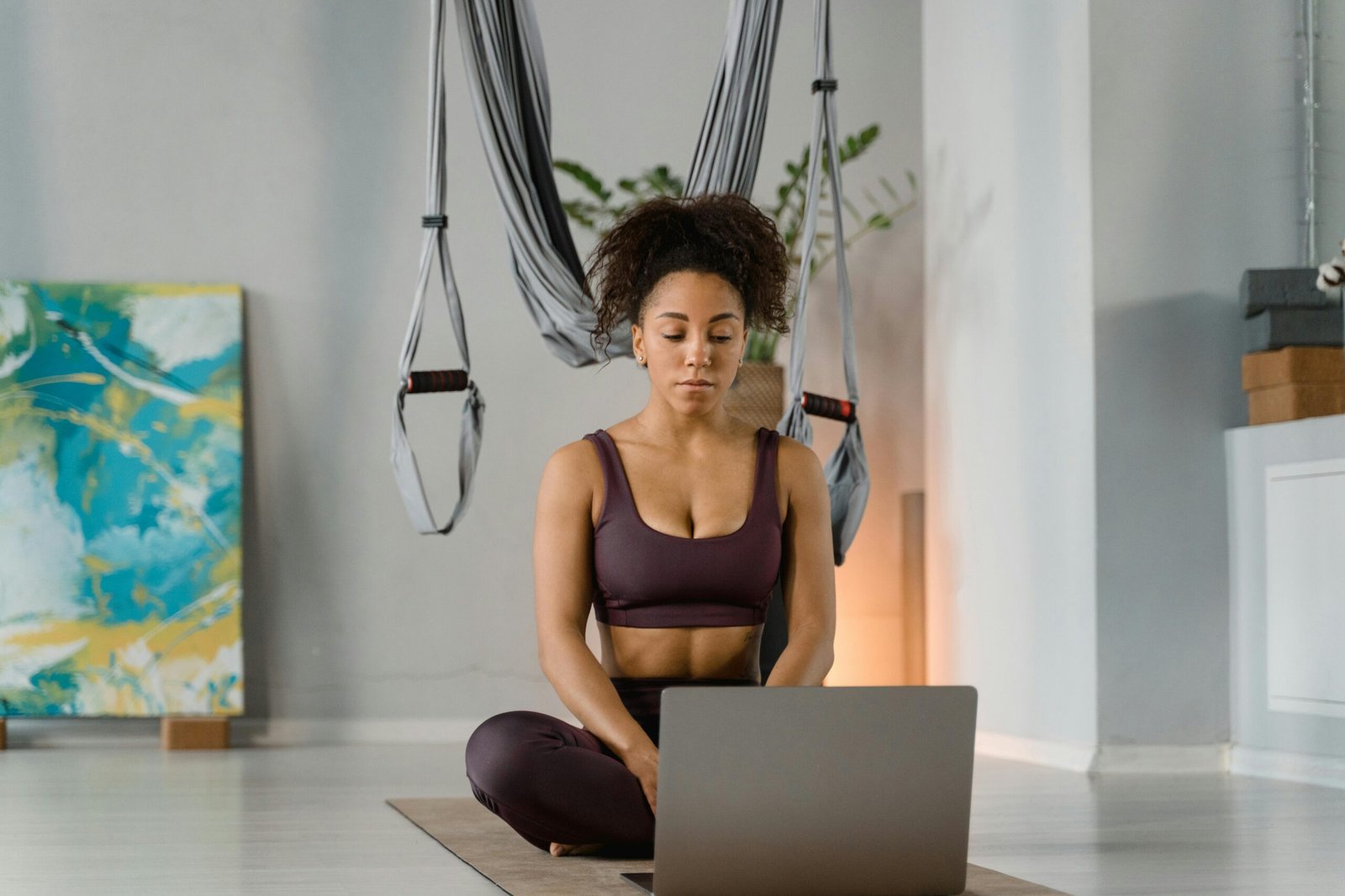 A woman practicing yoga at home with a laptop, focusing on fitness and mindfulness.