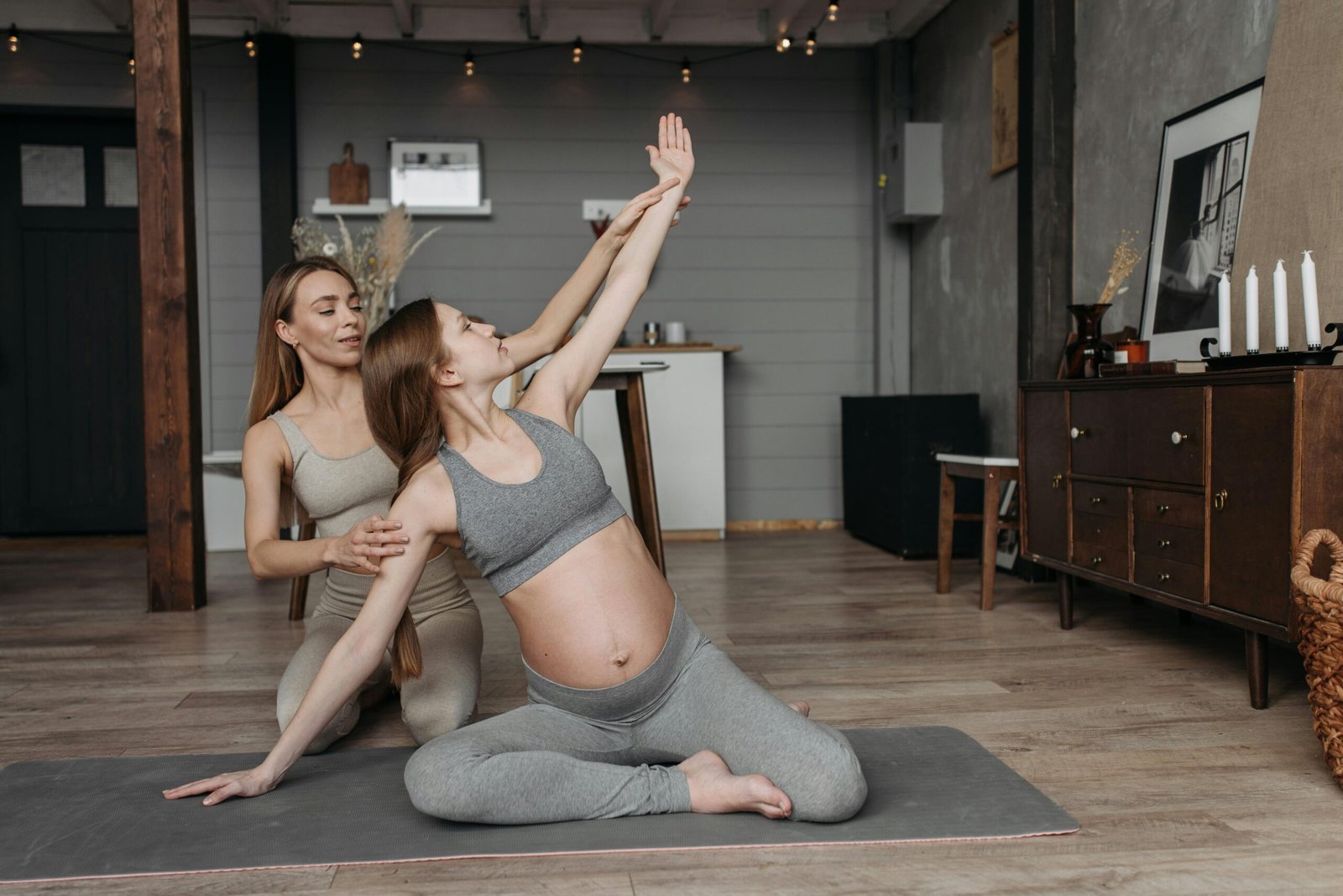 Pregnant woman on yoga mat with instructor, focusing on prenatal exercise.